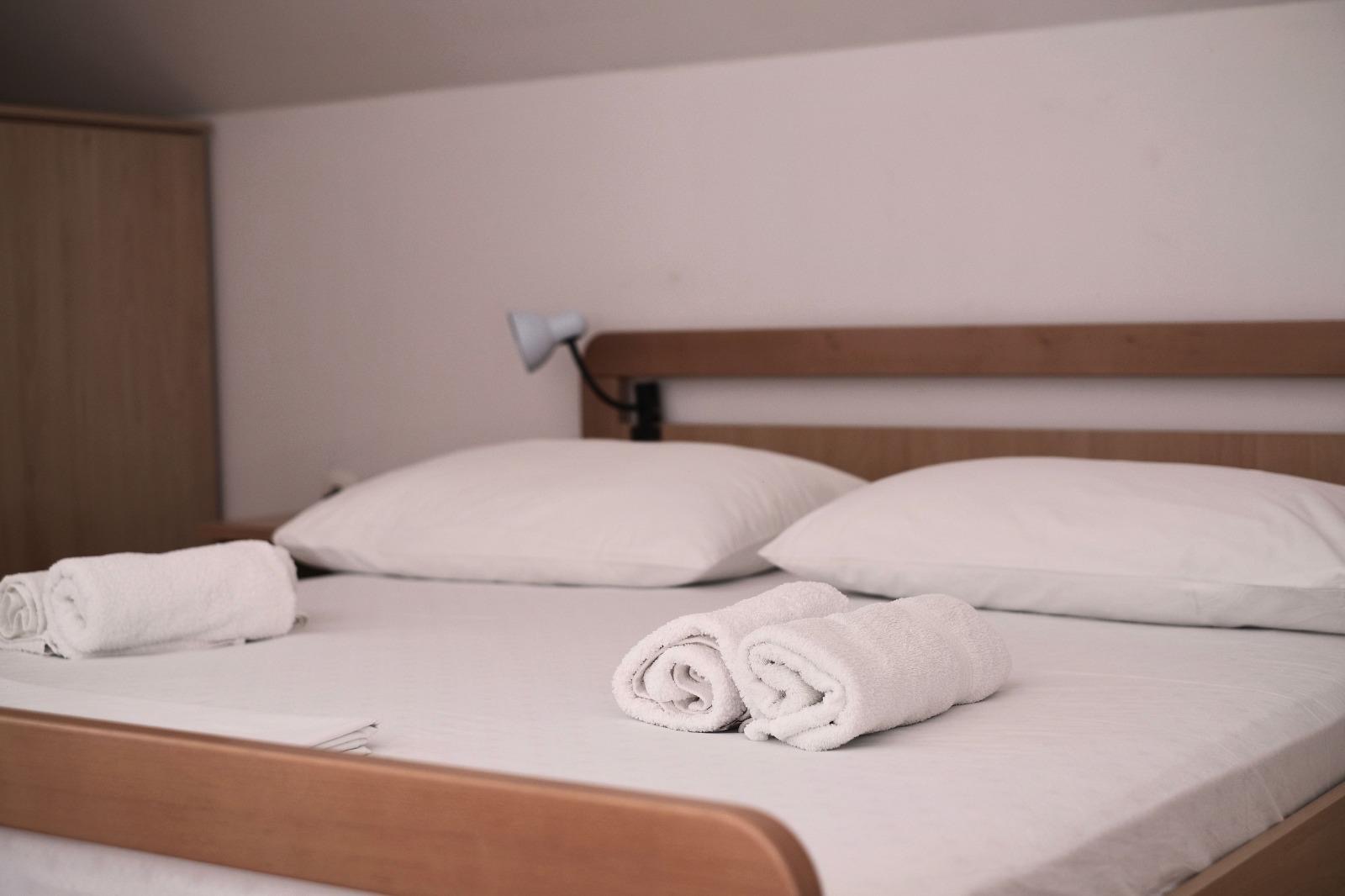 Bed with rolled towels prepared for arrival in the holiday apartment