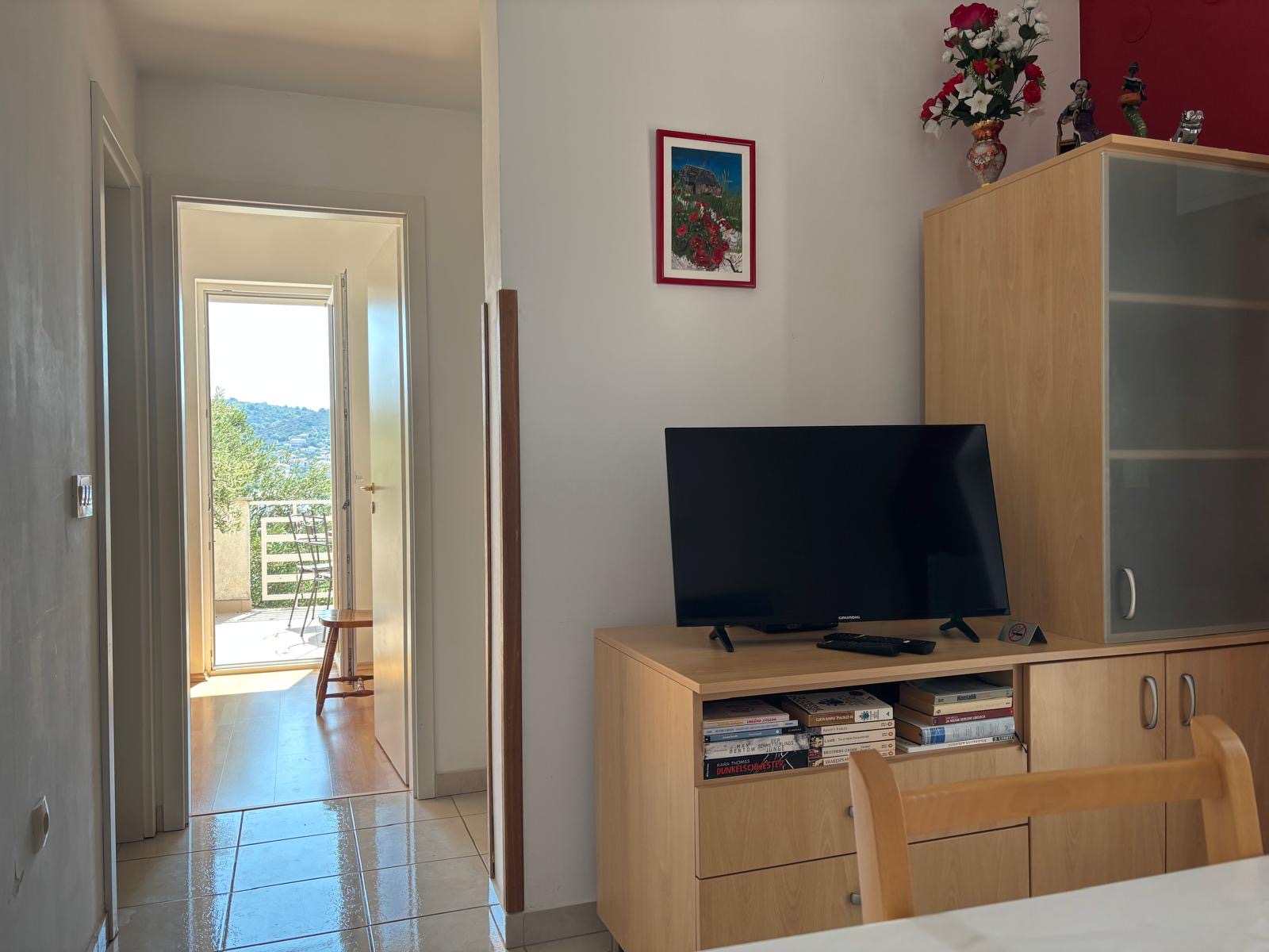 Living room with Smart TV and view to the sunny balcony and bay