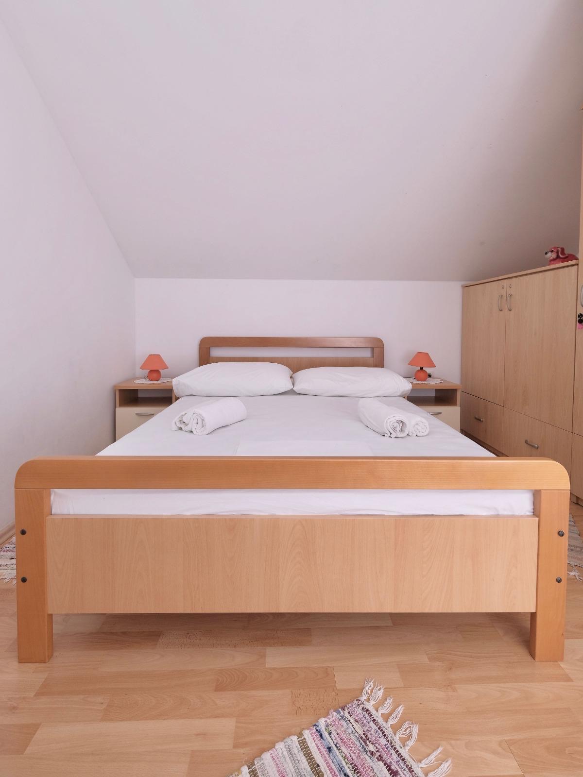 Bright bedroom with double bed and warm wood accents in Apartman Vinišće