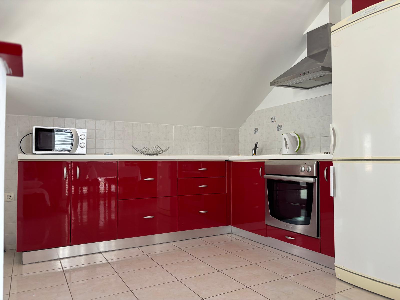 Fully equipped kitchen with red cabinetry and modern appliances